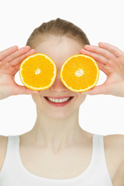 Close up of a woman placing oranges on her eyes — Stock Photo, Image