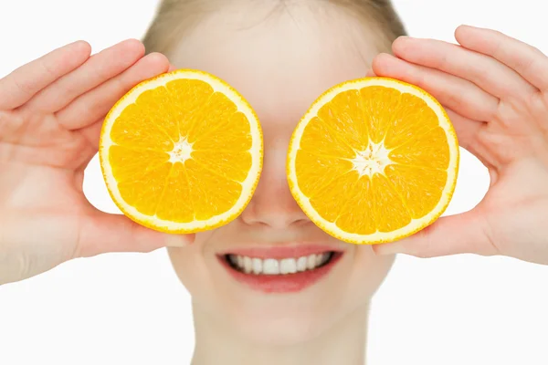 Close up de uma mulher alegre colocando laranjas em seus olhos — Fotografia de Stock