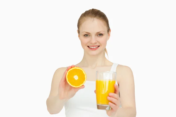 Fröhliche Frau präsentiert eine Orange, während sie ein Glas hält — Stockfoto