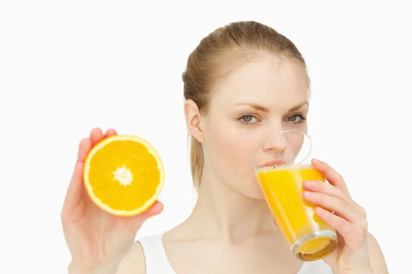 Woman presenting an orange while drinking — Stock Photo, Image