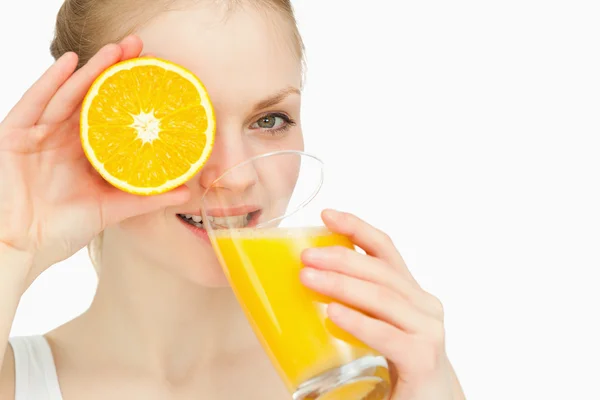 Woman placing an orange on her eye while drinking — Stock Photo, Image