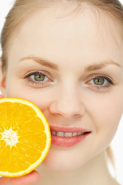 Close up of a woman placing an orange on her lips — Stock Photo, Image