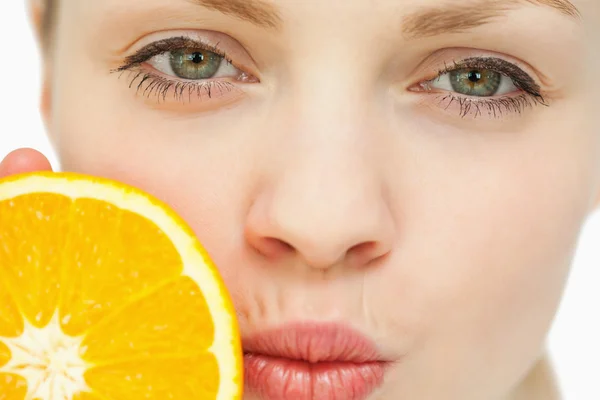 Close up of a woman placing an orange near her mouth — Stock Photo, Image