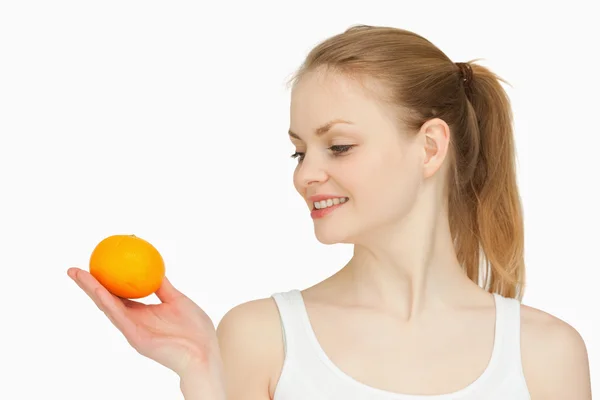 Frau hält eine Mandarine in der Hand, während sie sie ansieht — Stockfoto