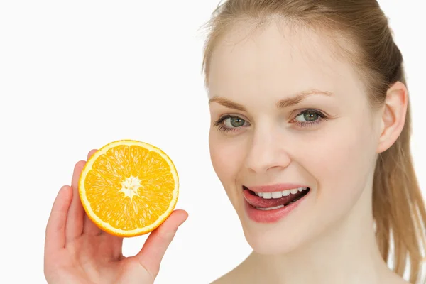 Mulher segurando uma laranja ao colocar a língua em seus lábios — Fotografia de Stock