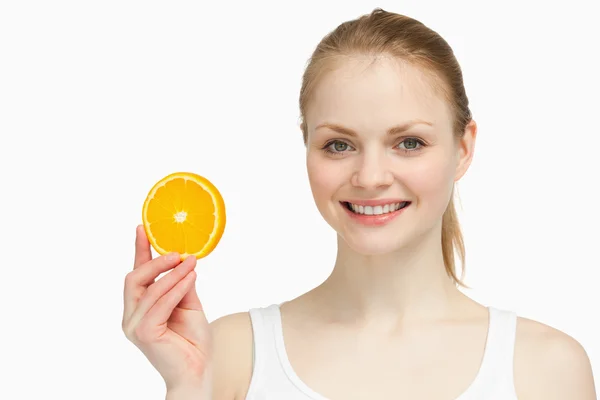 Mulher alegre apresentando uma fatia de laranja — Fotografia de Stock