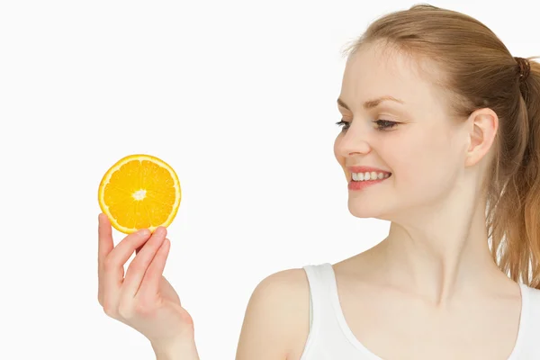 Γυναίκα, παρουσιάζοντας μία φέτα πορτοκάλι, ενώ κοιτώντας το — Φωτογραφία Αρχείου
