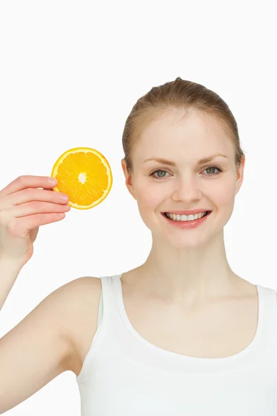 Mulher alegre segurando uma fatia de laranja — Fotografia de Stock