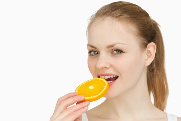 Frau legt sich eine Orangenscheibe in den Mund — Stockfoto