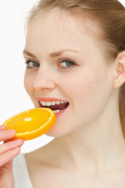 Close up of a woman placing an orange slice in her mouth — Stock Photo, Image