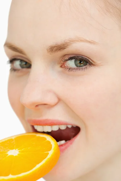 Close up de uma mulher colocando uma fatia de laranja na boca — Fotografia de Stock