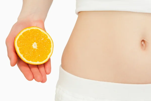 Mujer colocando una naranja cerca de su vientre — Foto de Stock