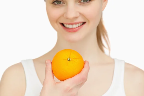 Fechar de uma mulher segurando uma laranja enquanto sorri — Fotografia de Stock