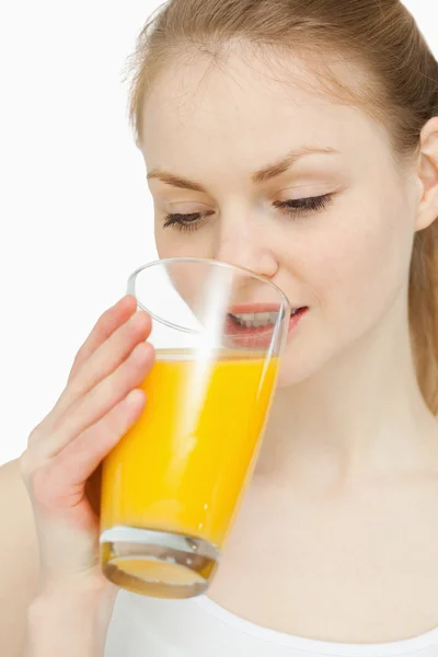 Mujer bebiendo un vaso de jugo de naranja mientras lo mira — Foto de Stock