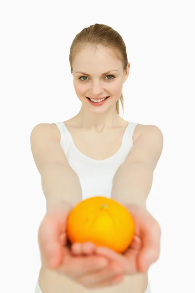 Lächelnde Frau präsentiert eine Mandarine — Stockfoto