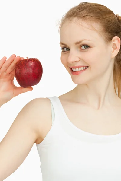 Mujer sosteniendo una manzana mientras sonríe — Foto de Stock