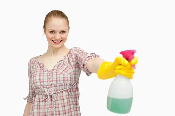 Mulher alegre segurando uma garrafa de spray enquanto sorri — Fotografia de Stock