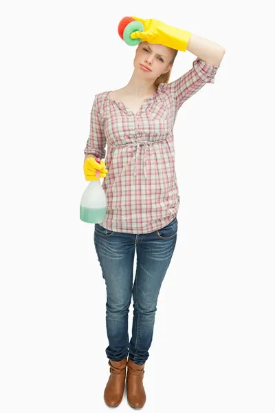 Woman wiping her forehead while holding a spray bottle — Stock Photo, Image