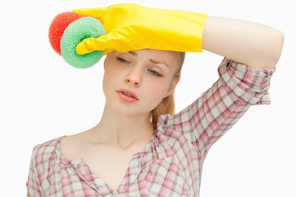 Mulher limpando a testa enquanto segurava esponjas — Fotografia de Stock