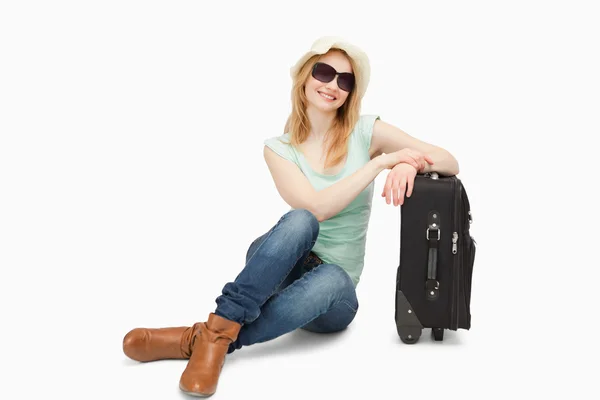 Женщина сидит рядом с чемоданом — стоковое фото