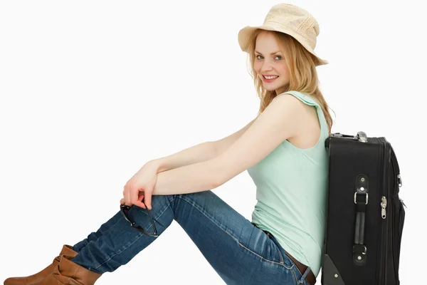 Радостная женщина сидит рядом с чемоданом — стоковое фото