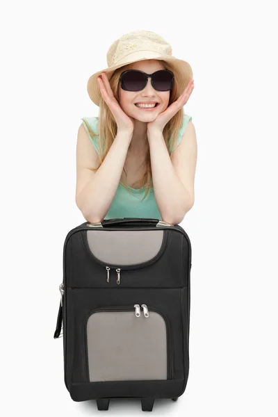 Cheerful woman leaning on a suitcase while sitting — Stock Photo, Image