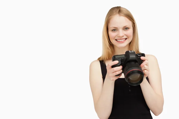 Mujer sosteniendo una cámara SLR mientras sonríe —  Fotos de Stock