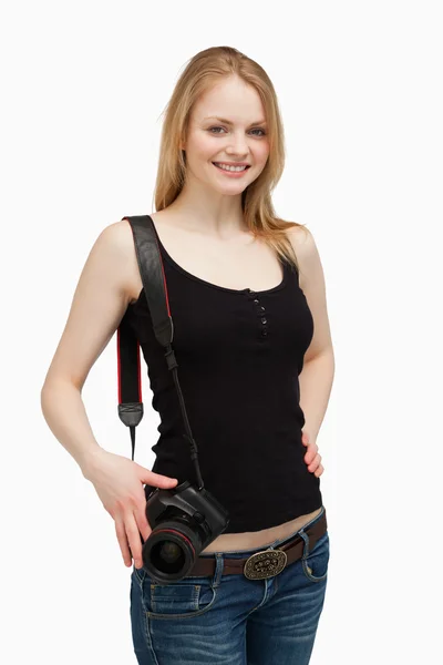 Woman smiling while carrying a camera — Stock Photo, Image