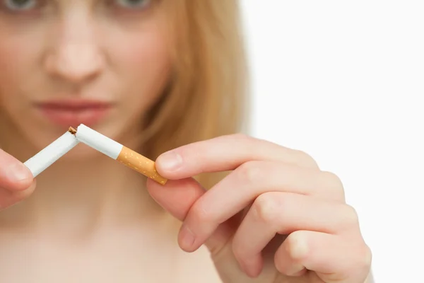 Fechar as mãos de uma mulher quebrando um cigarro — Fotografia de Stock