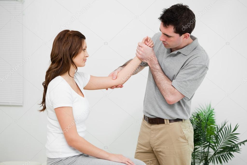 Serious practitioner touching the elbow of a woman ⬇ Stock Photo, Image
