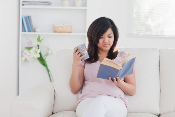 Vrouw met een mok en een boek — Stockfoto