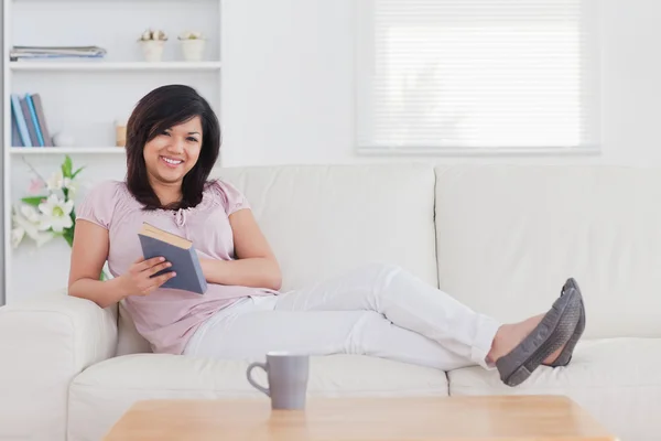 Mujer sonriente acostada en un sofá — Foto de Stock