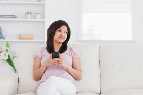 Frau sitzt auf einem Sofa und hält ein Telefon — Stockfoto