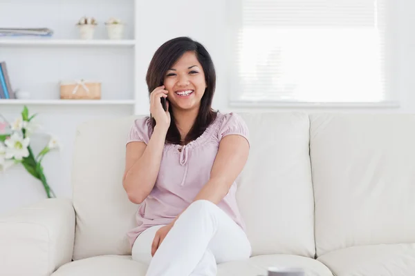 Lachende vrouw houdt van een telefoon en zittend op een bank — Stockfoto