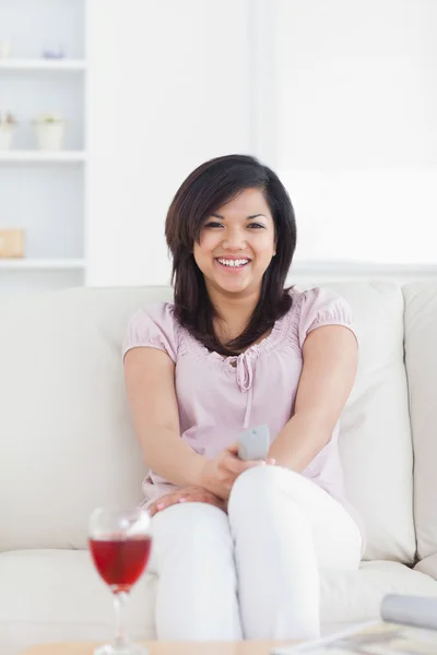 Uśmiechnięta kobieta siedzi na kanapie — Zdjęcie stockowe