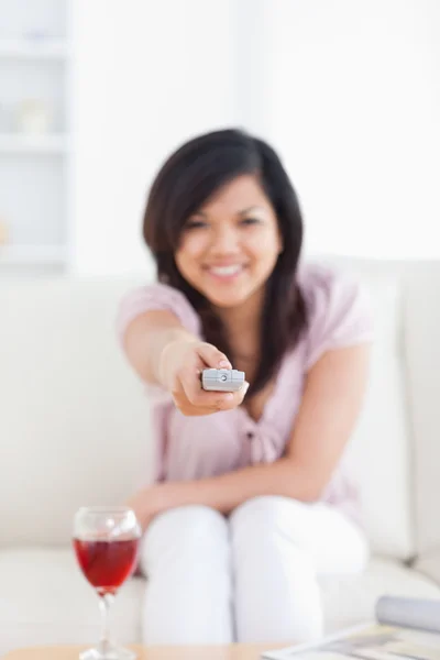 Blurred woman holding a television remote while sitting on a cou — Stock Photo, Image