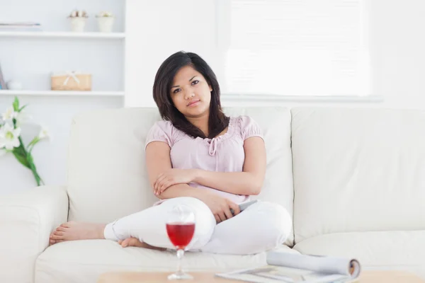 Vrouw zittend op een bank tijdens het oversteken van haar armen — Stockfoto