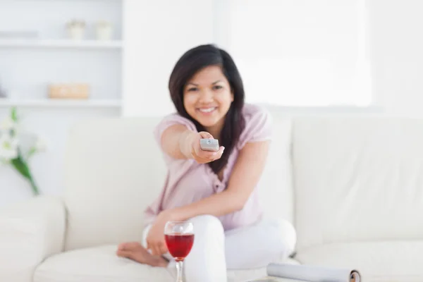 Mujer sosteniendo un mando a distancia mientras está sentado —  Fotos de Stock