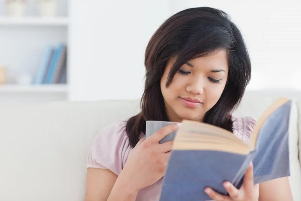 Frau liest ein Buch, während sie eine Tasse hält — Stockfoto