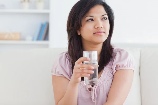 Mujer sentada en un sofá y sosteniendo un vaso — Foto de Stock