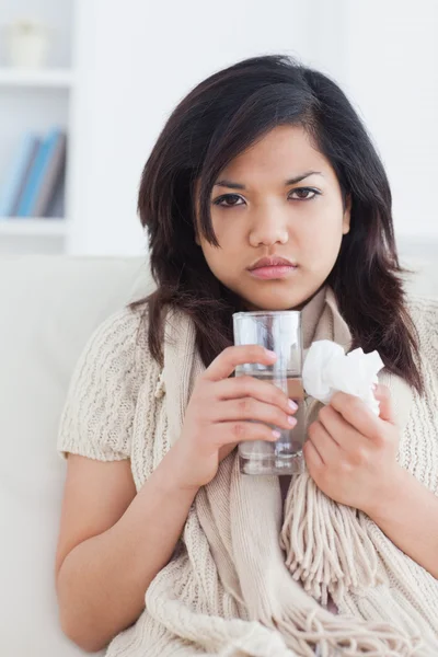 Zieke vrouw holding een weefsel en een glas water — Stockfoto