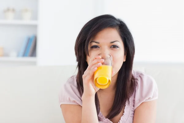 Mujer sonriendo mientras bebe un vaso de jugo de naranja — Foto de Stock