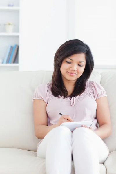 Vrouw schrijven op een notitieblok zittend op een bank — Stockfoto