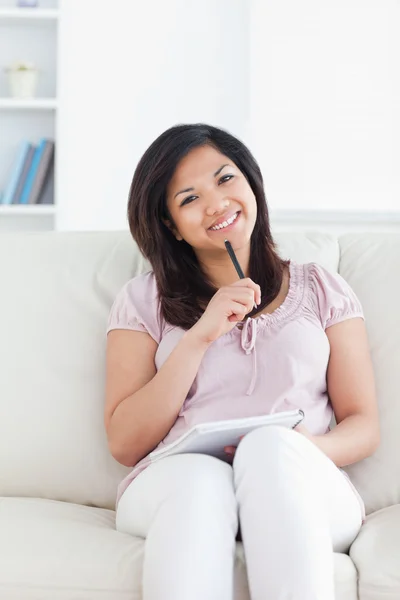 Woman smiling and holding a pen and a notebook — Stock Photo, Image