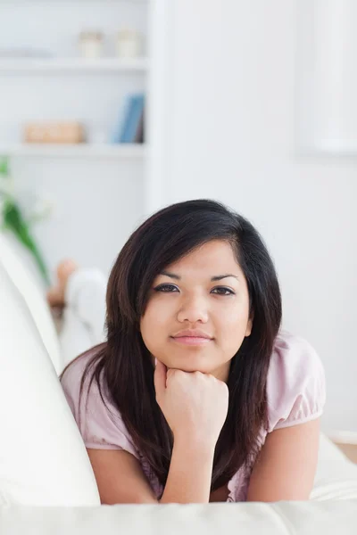 Vrouw ontspannen op een bank holding haar hoofd met haar vuist — Stockfoto