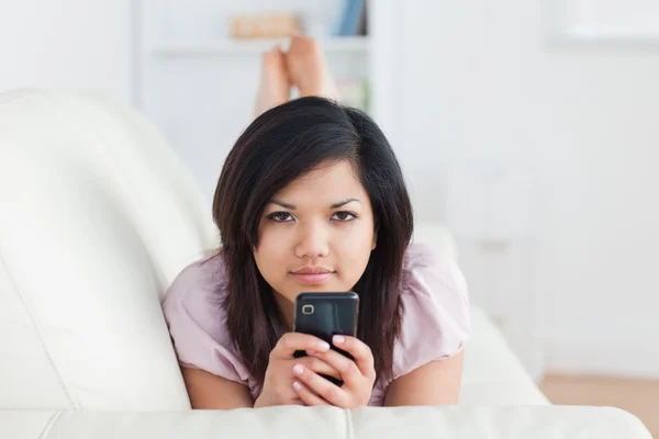 Žena odpočívá na gauči při držení telefonu — Stock fotografie