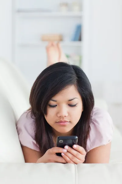 Žena ležela na pohovce, při pohledu na telefon — Stock fotografie