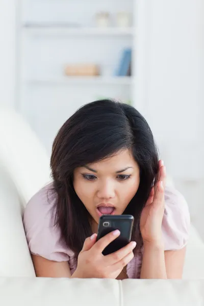Chocked vrouw bellen terwijl rusten op een sofa — Stockfoto