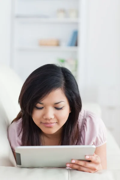 Mujer acostada en un sofá mientras mira una tableta — Foto de Stock