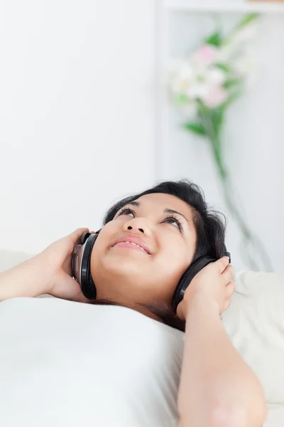 Γυναίκα ξαπλωμένη σε έναν καναπέ με τα ακουστικά για — Φωτογραφία Αρχείου